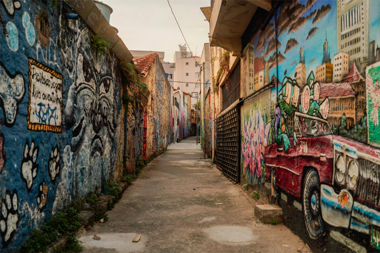 Graffiti-covered alleyway with colorful murals on walls and a vintage car.